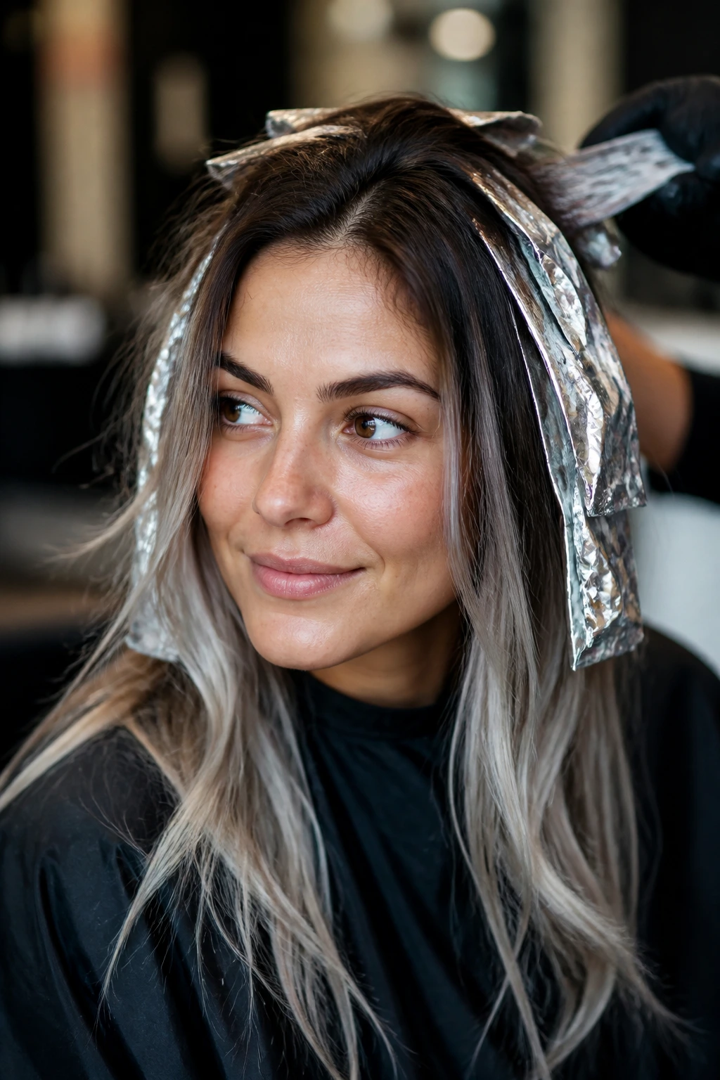 Portrait of a woman in a salon chair discussing hair color with a colorist off-frame