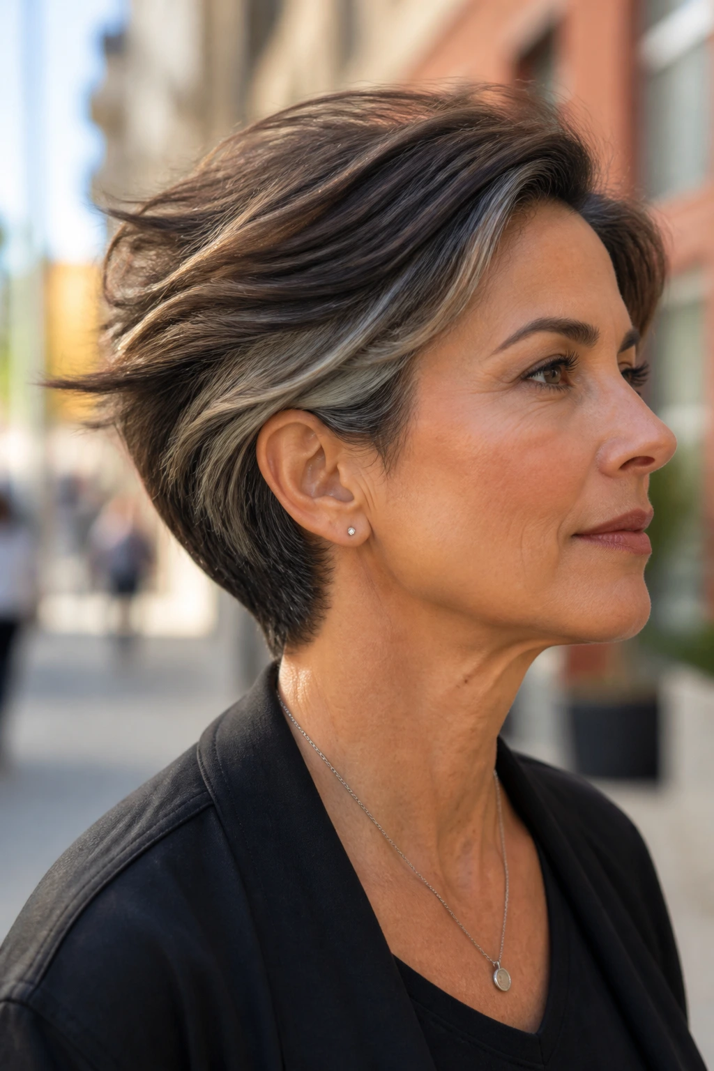 Close-up of real person with tapered cut showing brown top and smoky grey underlayers in breeze