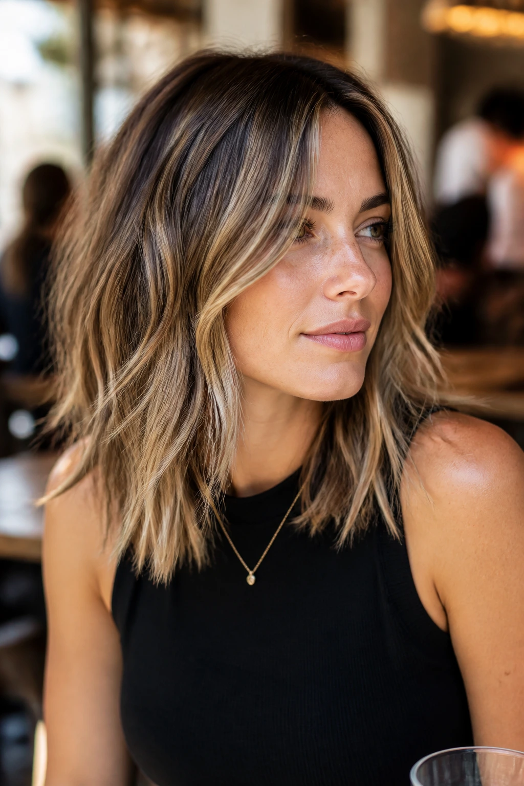 Medium close-up of a real woman with textured midlength hair and piecey ends showing blonde highlights.