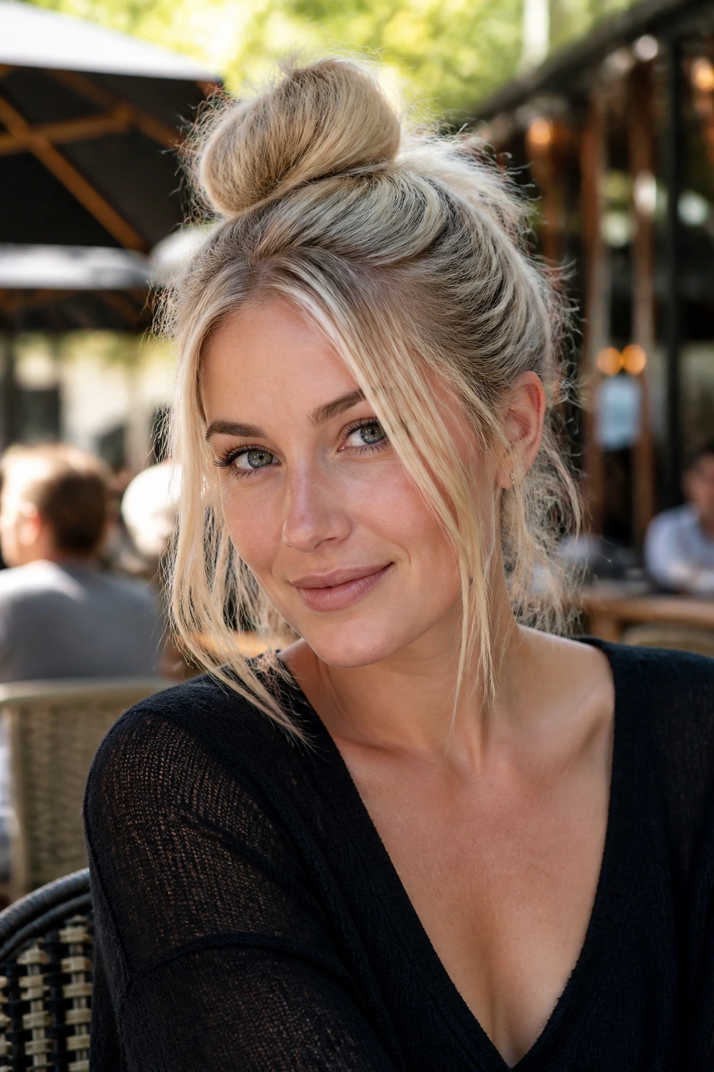 Portrait of a woman with a messy top knot and wispy front pieces in cool blonde