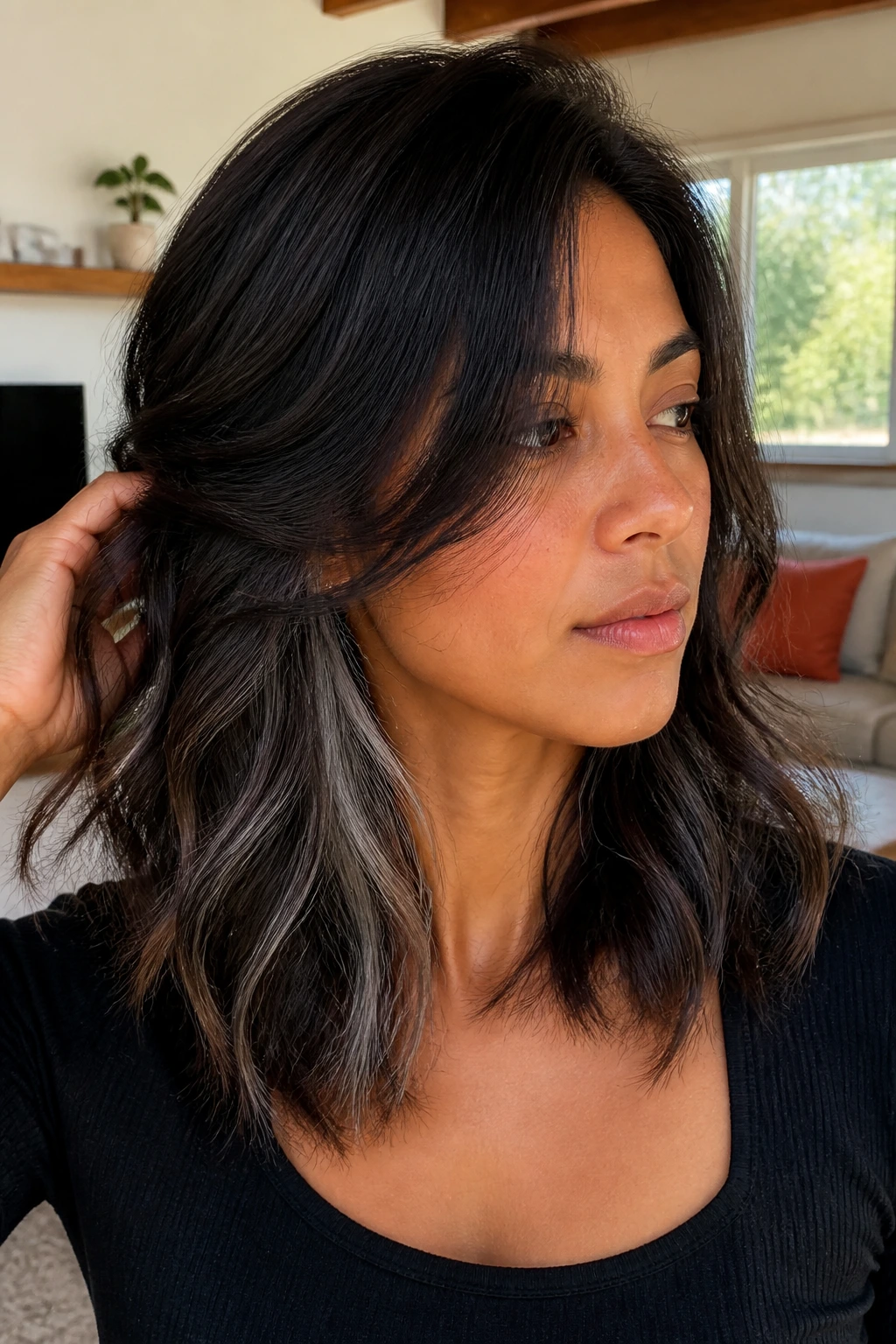 Close-up of a real person with tousled midi-length hair and peekaboo smoky grey underlayers