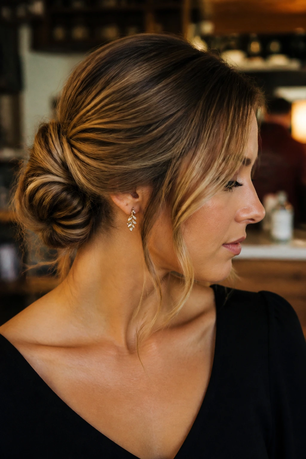 Shoulder-length hair in a low knot with tucked roll and side strands, warm indoor setting