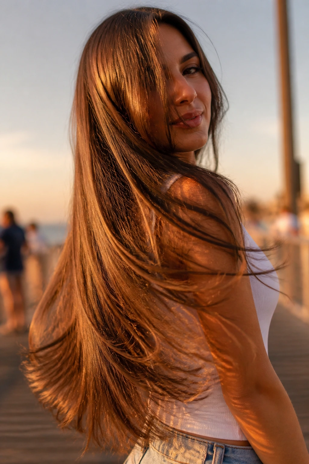 Woman with waist-length feathered hair showing movement at the hem in golden hour light