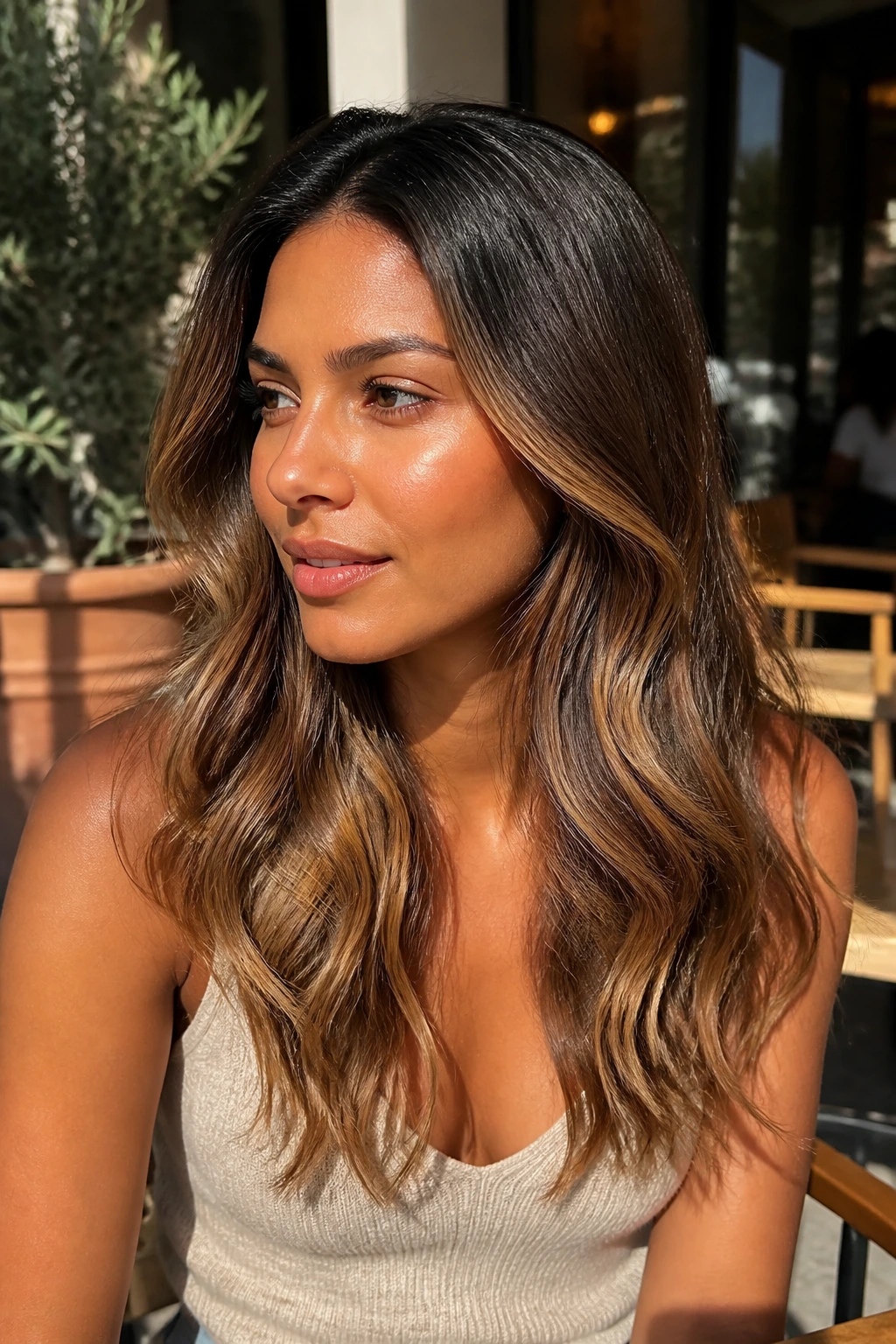Close-up of a real woman with bronzed caramel waves and shadow roots in natural light