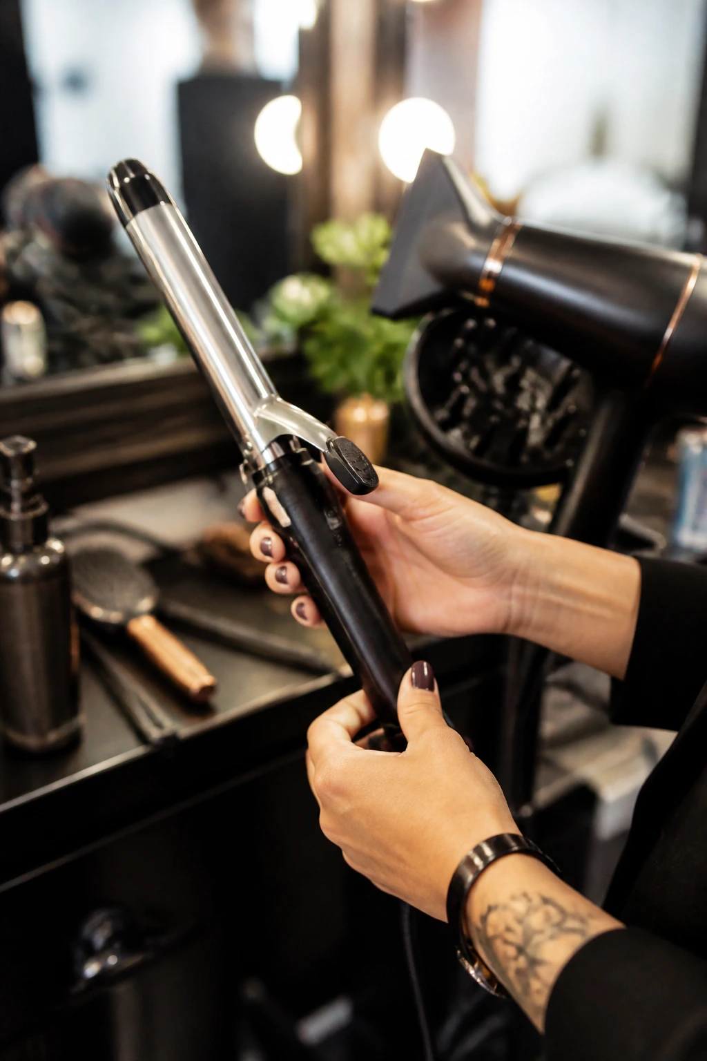 Hands holding a curling iron in a salon with tools subtly visible