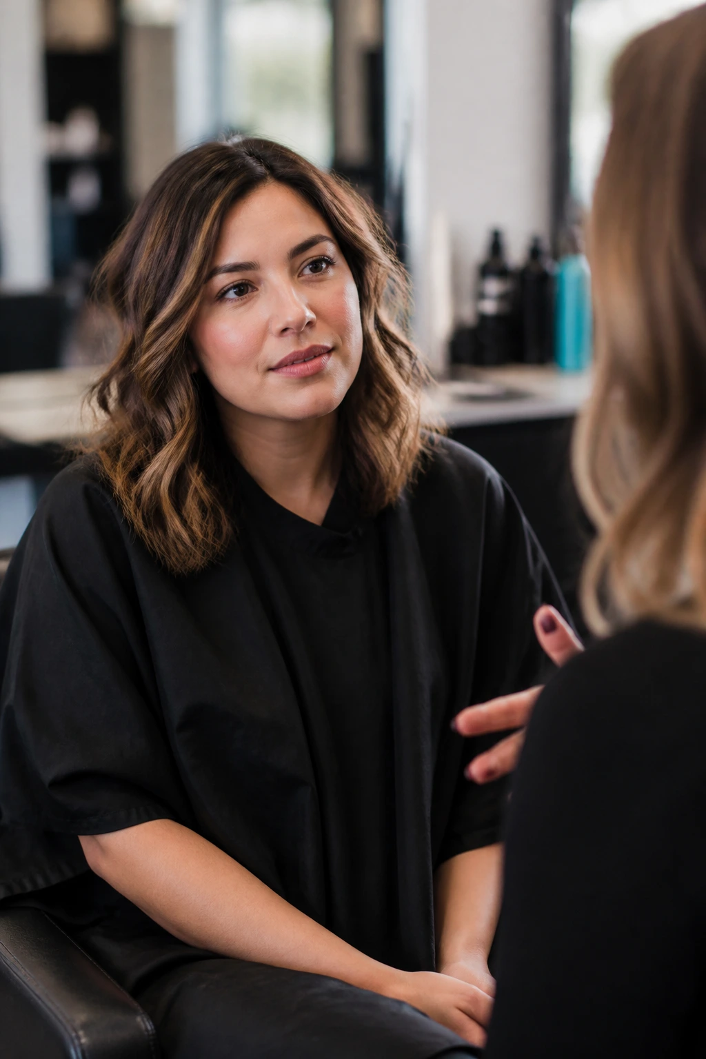 Client in salon chair discussing wavy haircut options with stylist
