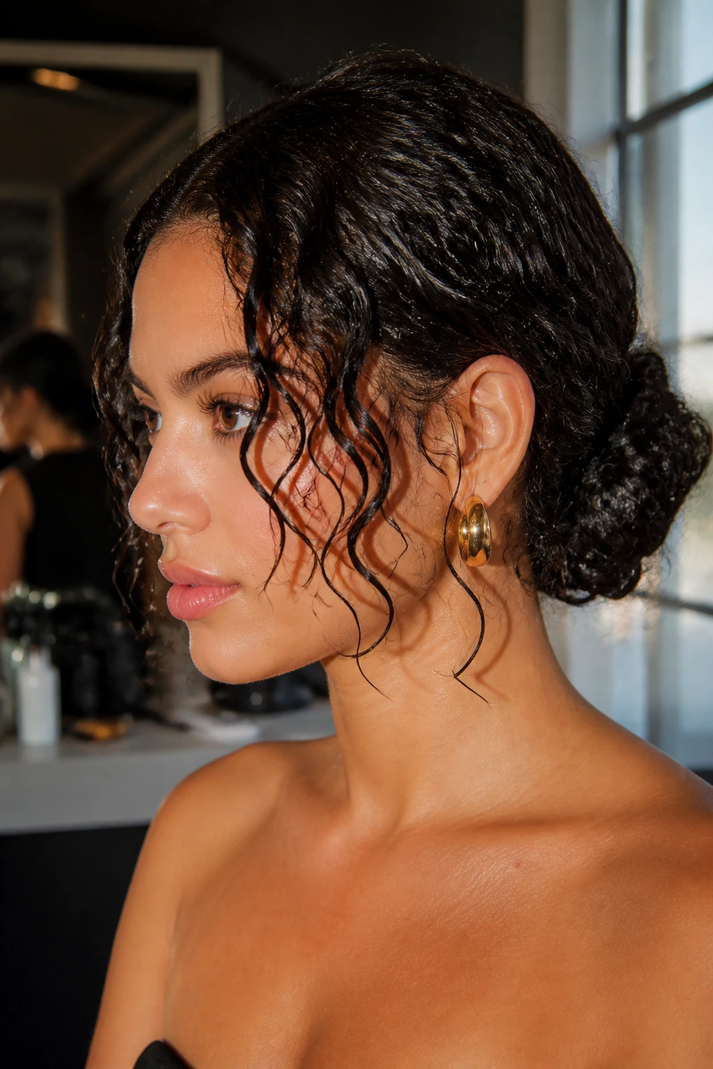Close-up of a real person with glossy wet-look bun and face-framing curls