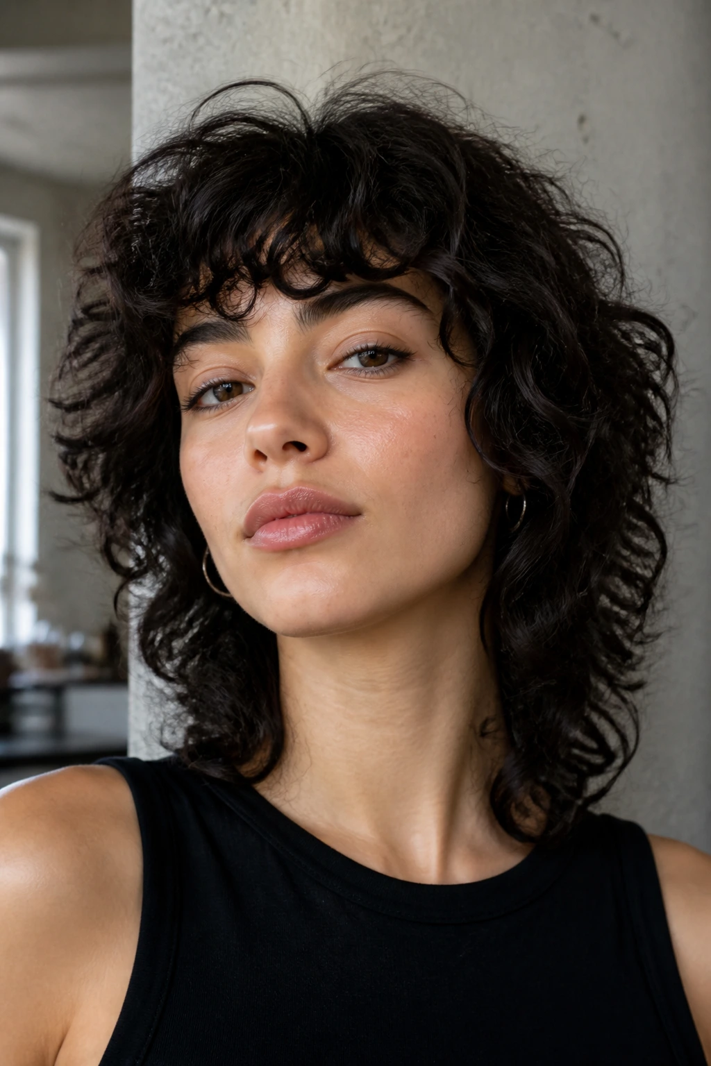 Close-up of a real woman with short layered wolf cut bangs blending into curly hair