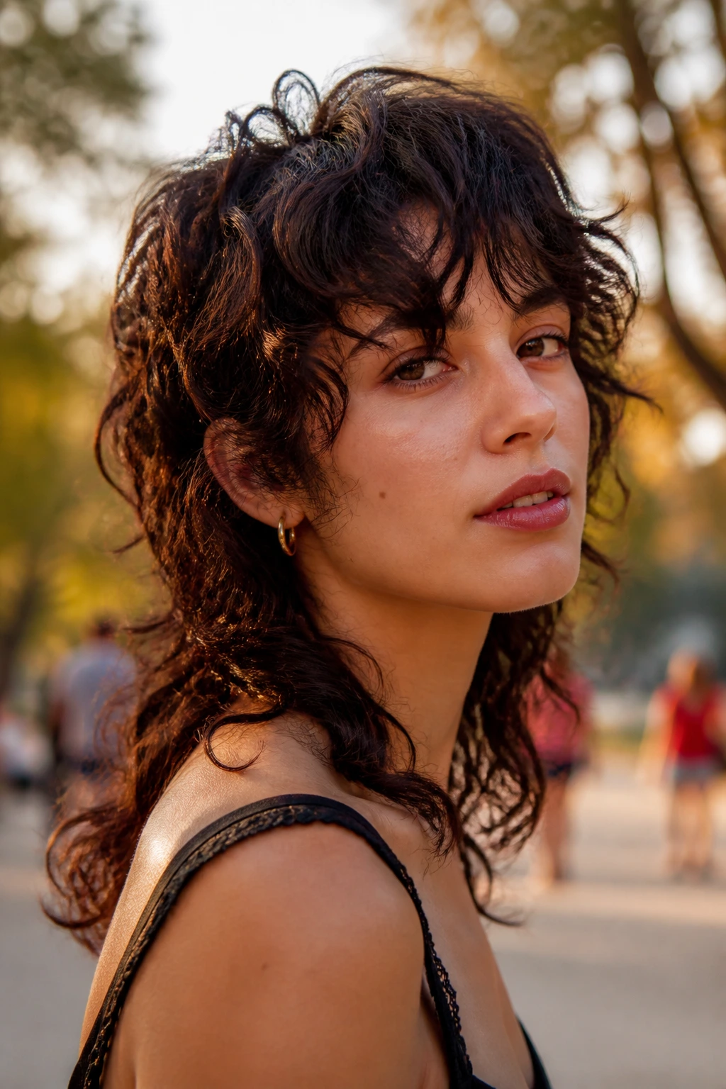 Real woman with curly wolf cut and wispy fringe in outdoor golden hour light