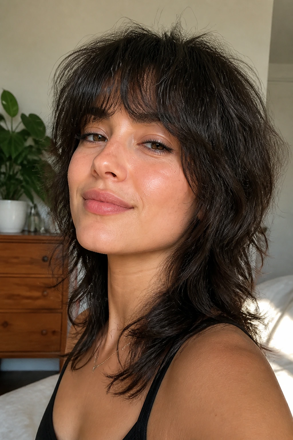 Close-up portrait of a real woman with a wolf cut, showcasing crown lift and movement in a sunlit bedroom.